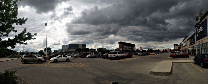 Cars on road against cloudy sky