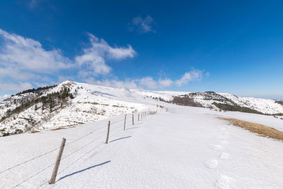 Scenic view of snow covered mountains against blue sky