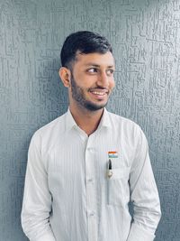 Portrait of young man standing against wall