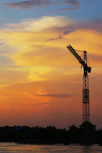Silhouette crane against sky during sunset