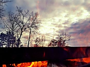 Low angle view of bare trees against cloudy sky