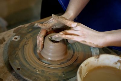 Cropped hands making earthenware pottery wheel at workshop