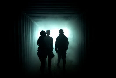 Silhouette of people in a dark misty room. light at the end of the tunnel