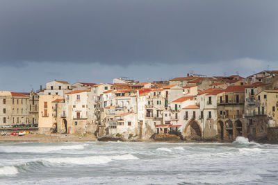 Buildings by sea against sky