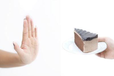 Close-up of hand holding chocolate over white background