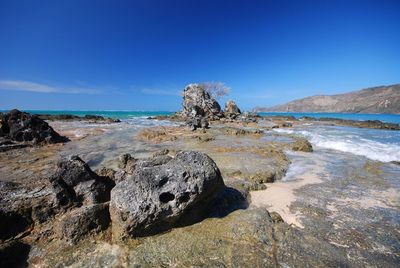 Rocks on beach against blue sky