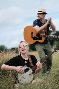 Young woman playing guitar on field