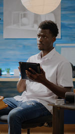 Young man using mobile phone while sitting on seat