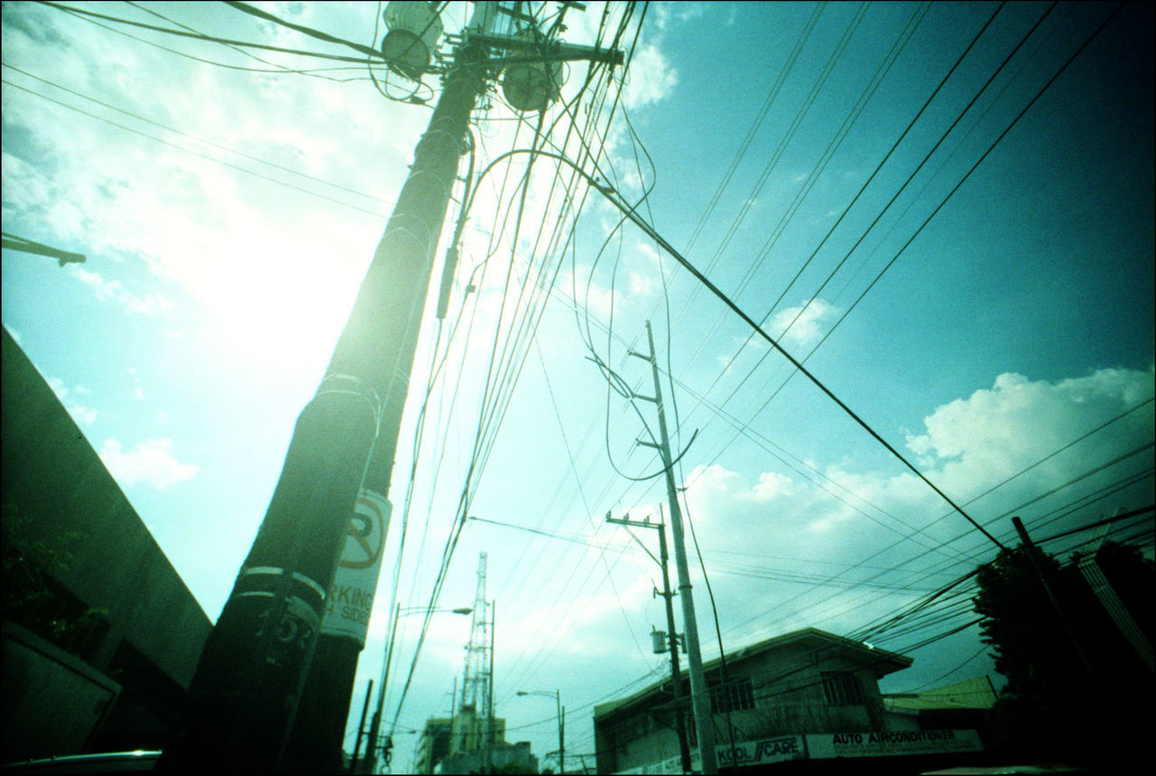 LOW ANGLE VIEW OF ELECTRICITY PYLON AGAINST BUILDINGS IN CITY