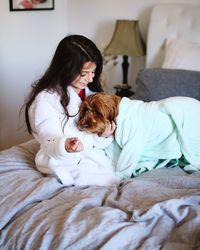 Woman with dog on bed at home