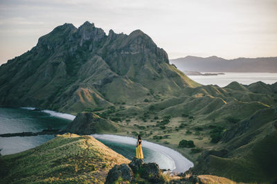 Rear view of man looking at mountains against sky