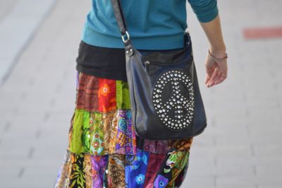 Midsection of woman with purse walking on footpath