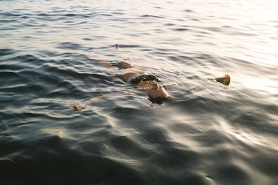 Woman swimming in sea at sunset