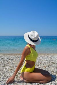 Man wearing hat on beach against clear blue sky