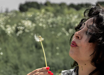 Close-up of woman blowing dandelion outdoors