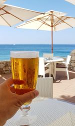 Sunny and bright summer a glass of beer in a beach bar with the blue sea in the background.