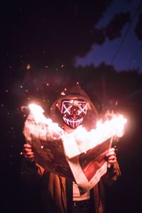 Digital composite image of man holding lit up at night