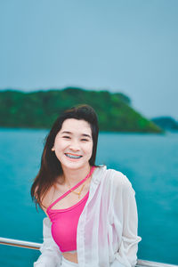 Portrait of young woman standing against sea