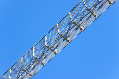 Low angle view of crane against clear blue sky