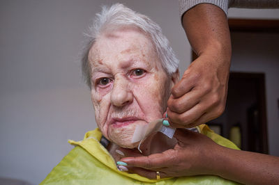 Elderly woman receiving facial hair removal from african american caregiver