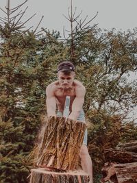 Low angle view of shirtless man standing by tree against sky