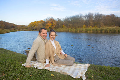 Portrait of happy friends standing on lake against plants