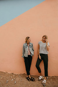 Full length of young woman standing against wall