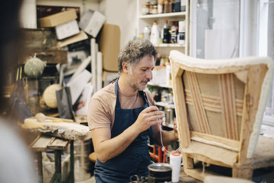 Craftsperson stitching chair in workshop