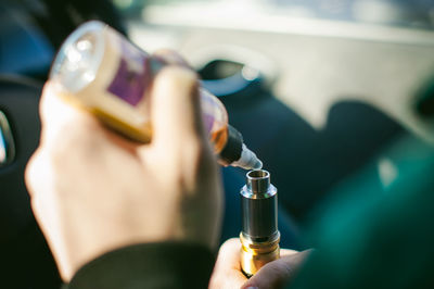 Cropped hand of person holding drop over electronic cigarette