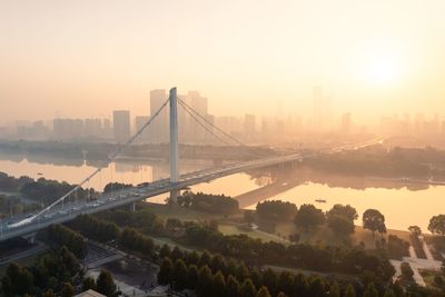 Suspension bridge over river against sky during sunset