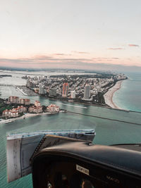 Aerial view of buildings and sea against sky during sunset