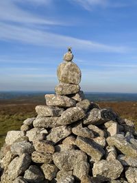 Stack of stones on rock at beach against sky