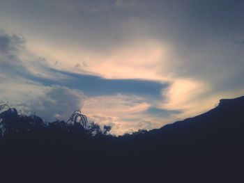 Silhouette of trees against cloudy sky