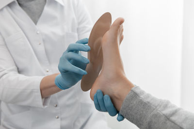 Midsection of doctor measuring sole holding patient foot