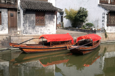 Boats moored in canal by building