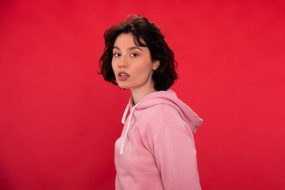 Portrait of beautiful young woman against red background