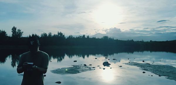 Reflection of man standing in lake against sky