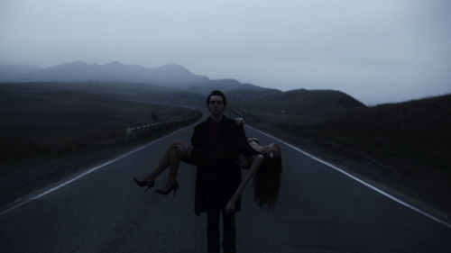 Portrait of woman standing on road against mountain