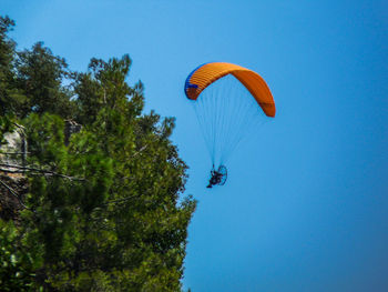 Low angle view of person paragliding in clear sky