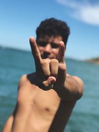 Shirtless man gesturing against sky