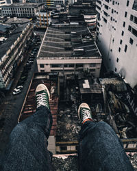 Low section of person sitting against building