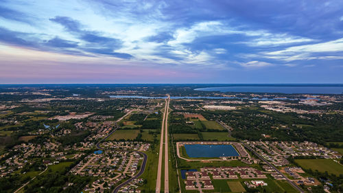 Sun sets creating a red and blue sky the highway below runs through the land of houses 