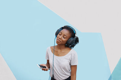 Low angle view of young woman standing against blue background