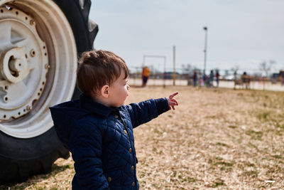 Little boy next to a huge tractor wheel at the county fair