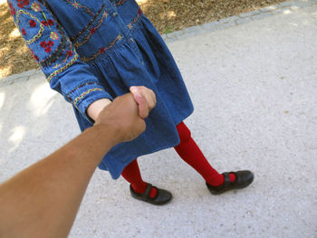 Low section of couple holding hands on street 