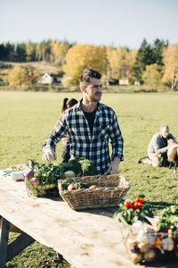 Mid adult man selling organic vegetables on table at farmer's market