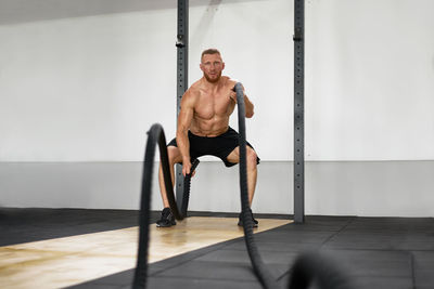 Full length of shirtless man exercising at gym