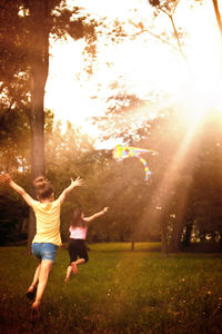 Rear view of carefree girl having fun while running with raised arms in spring day.