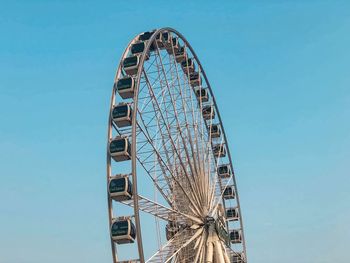 Low angle view of ferris wheel against clear blue sky