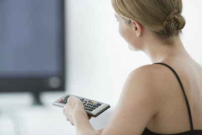 Close-up of woman changing tv channel at home